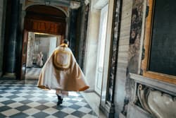 Thumbnail for an image displaying: A bishop hurries through St. Peter's Basilica, as a woman wearing a surgical mask watches.