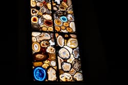 Thumbnail for an image displaying: A modern stained glass window, constructed from geodes, on a black background.