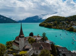 Thumbnail for an image displaying: A Swiss lake and Spiez castle, with boats in the harbor.