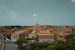 Thumbnail for an image displaying: St. Peter's Basilica, viewed from afar, with a single cloud above it.